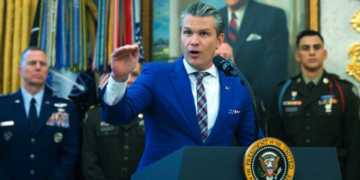 War Secretary Pete Hegseth speaks at a White House podium with military personnel behind him