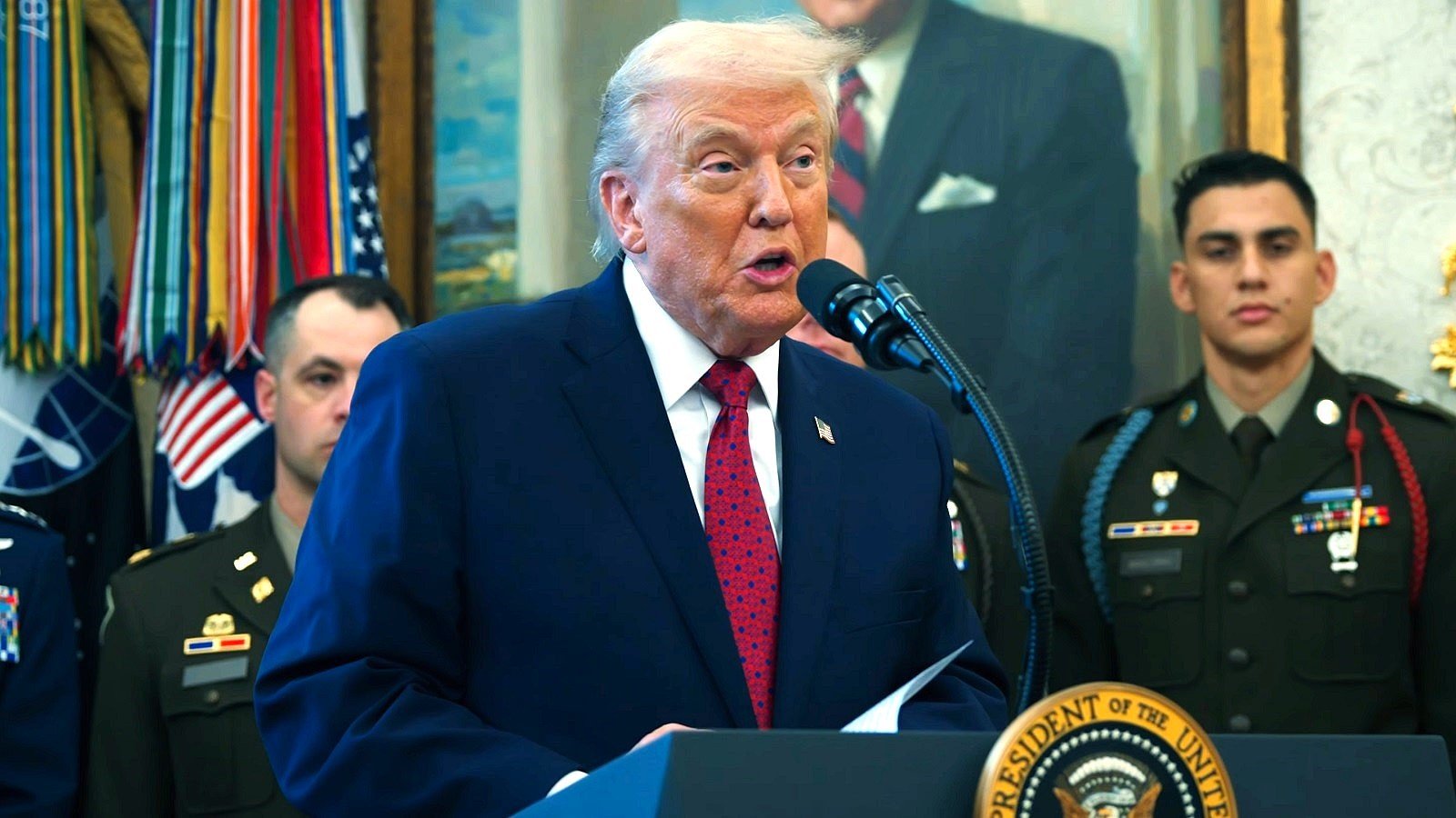 President Trump speaking at the presidential podium with U.S. service members behind him