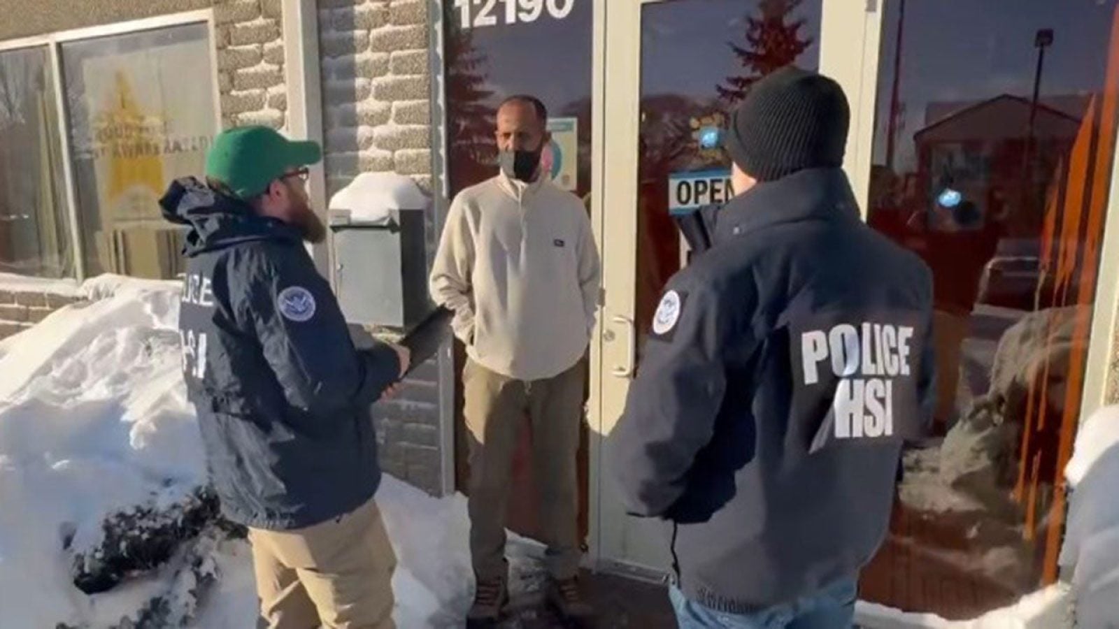 Homeland Security Investigations agents speak with a man outside a Minnesota business during a federal fraud investigation.