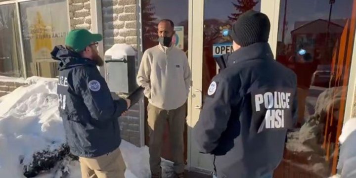 Homeland Security Investigations agents speak with a man outside a Minnesota business during a federal fraud investigation.