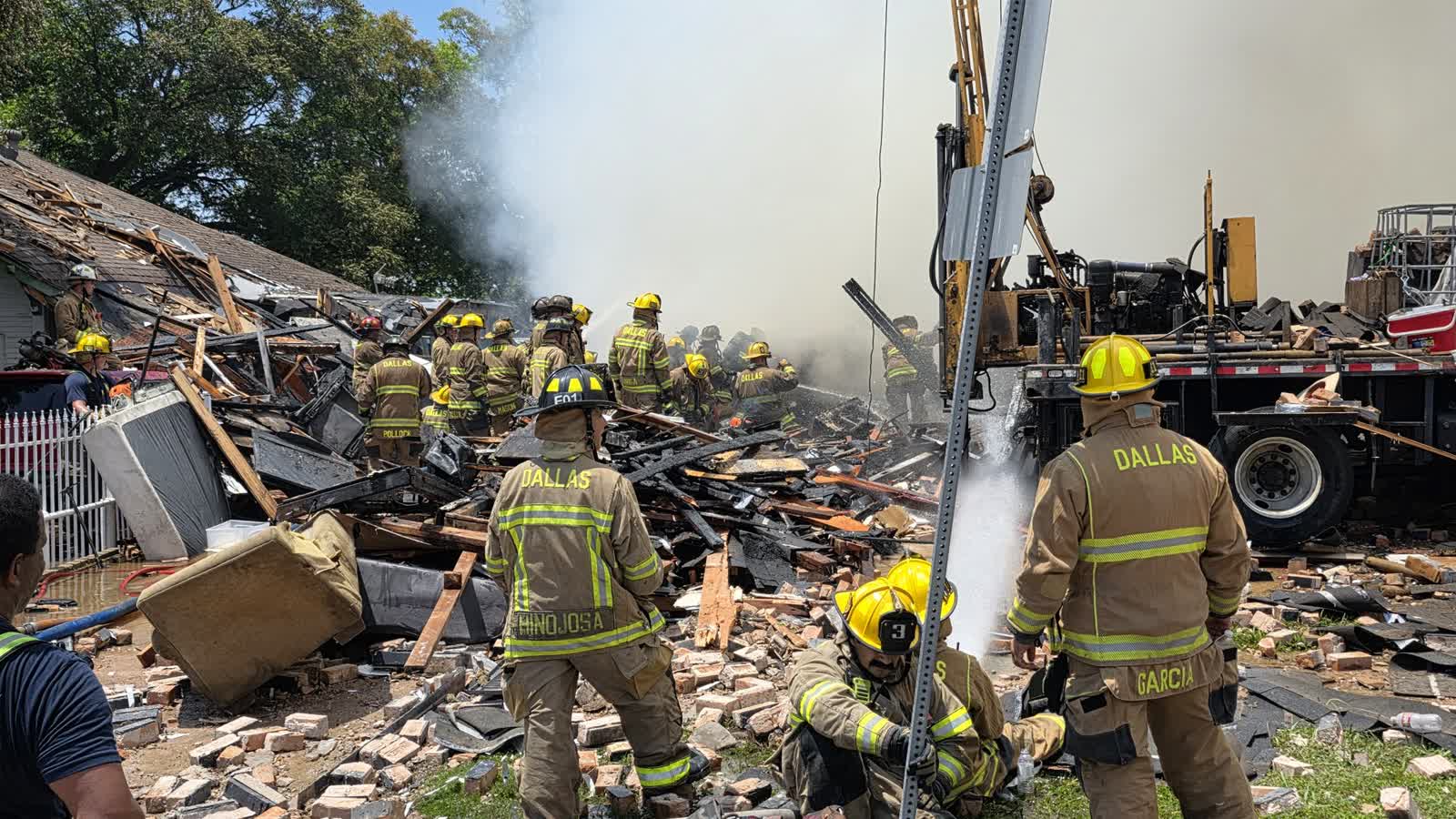 Dallas firefighters work through rubble and smoke after the apartment explosion on East 9th Street in Oak Cliff