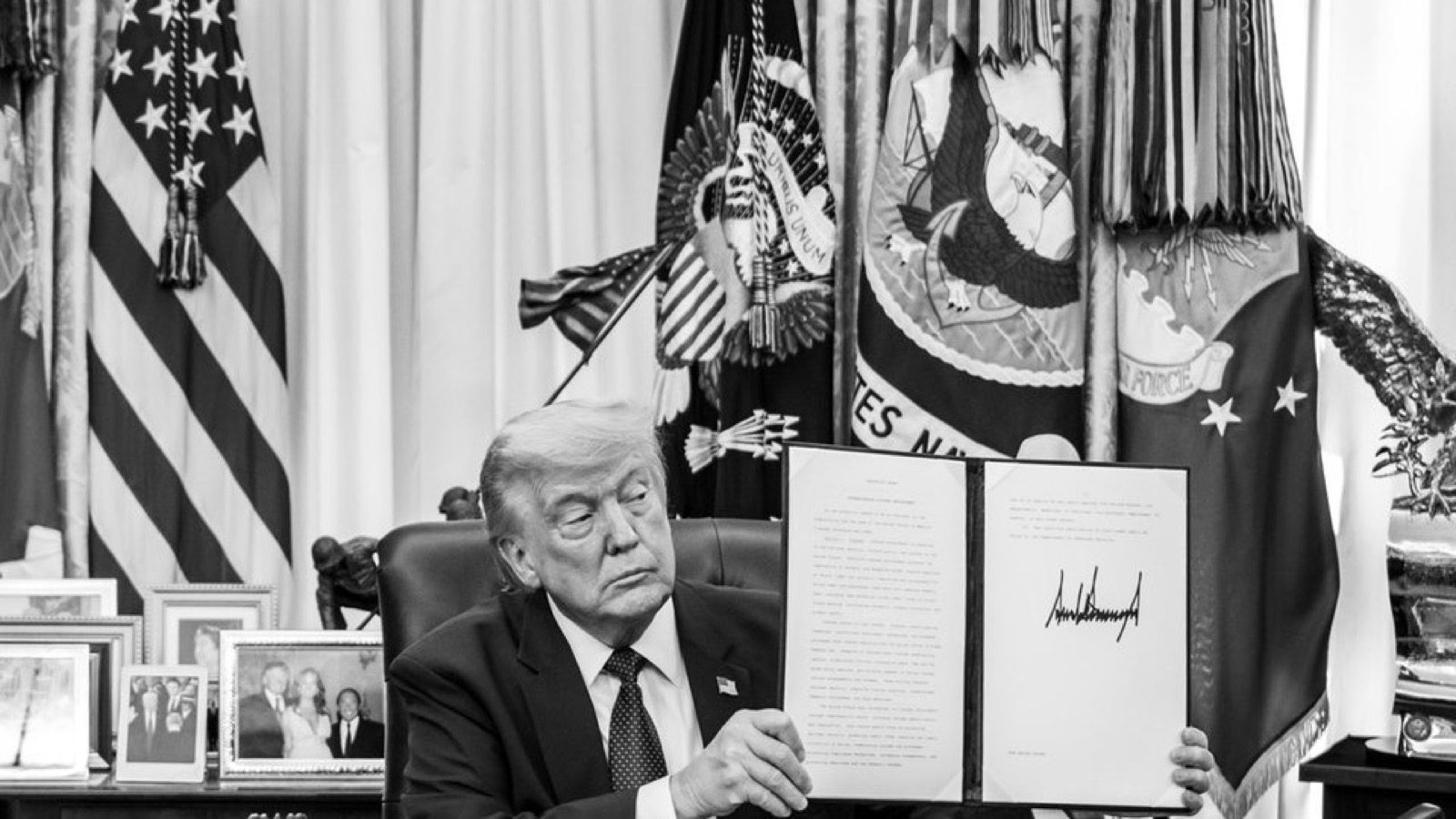 President Trump holds a signed customs enforcement order in the Oval Office