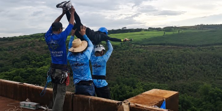 Operators position a person for a rope jump over a green valley