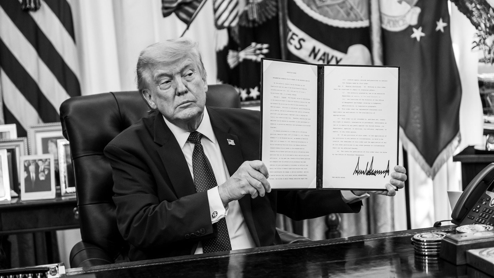 President Trump holds a signed document in the Oval Office