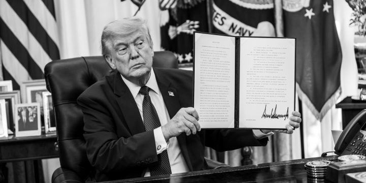 President Trump holds a signed document in the Oval Office