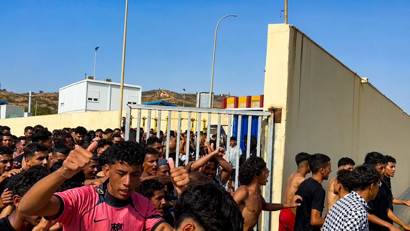 Crowd of young men moving through an open border gate in Ceuta, Spain