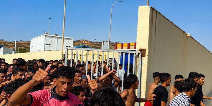 Crowd of young men moving through an open border gate in Ceuta, Spain