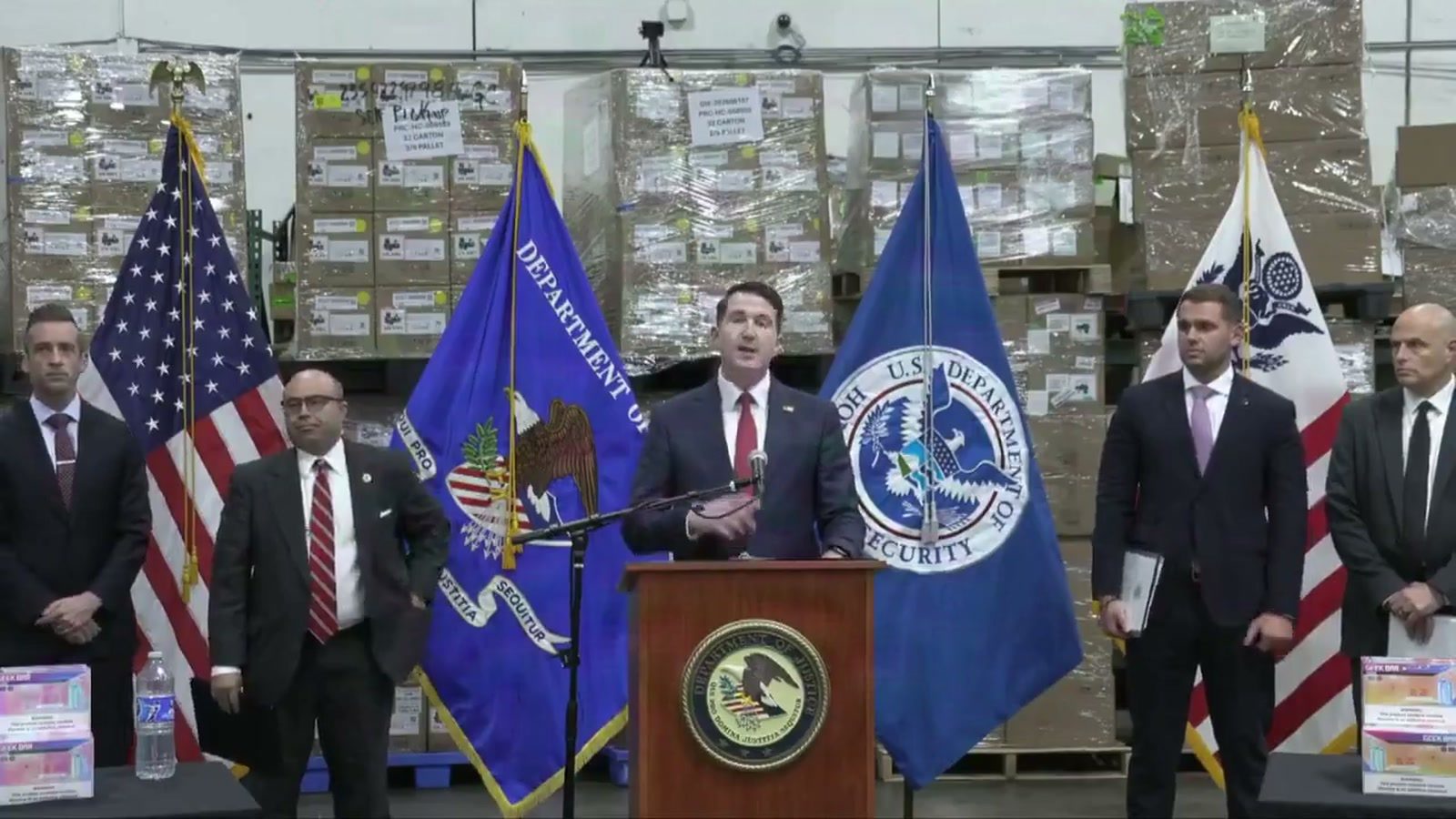 Assistant Attorney General Colin McDonald and federal law-enforcement officials announce the Trade Fraud Task Force milestone beside U.S., Justice Department and Homeland Security flags