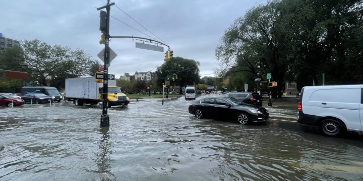 File photo shows cars and trucks moving through floodwater at a New York City intersection near Prospect Park