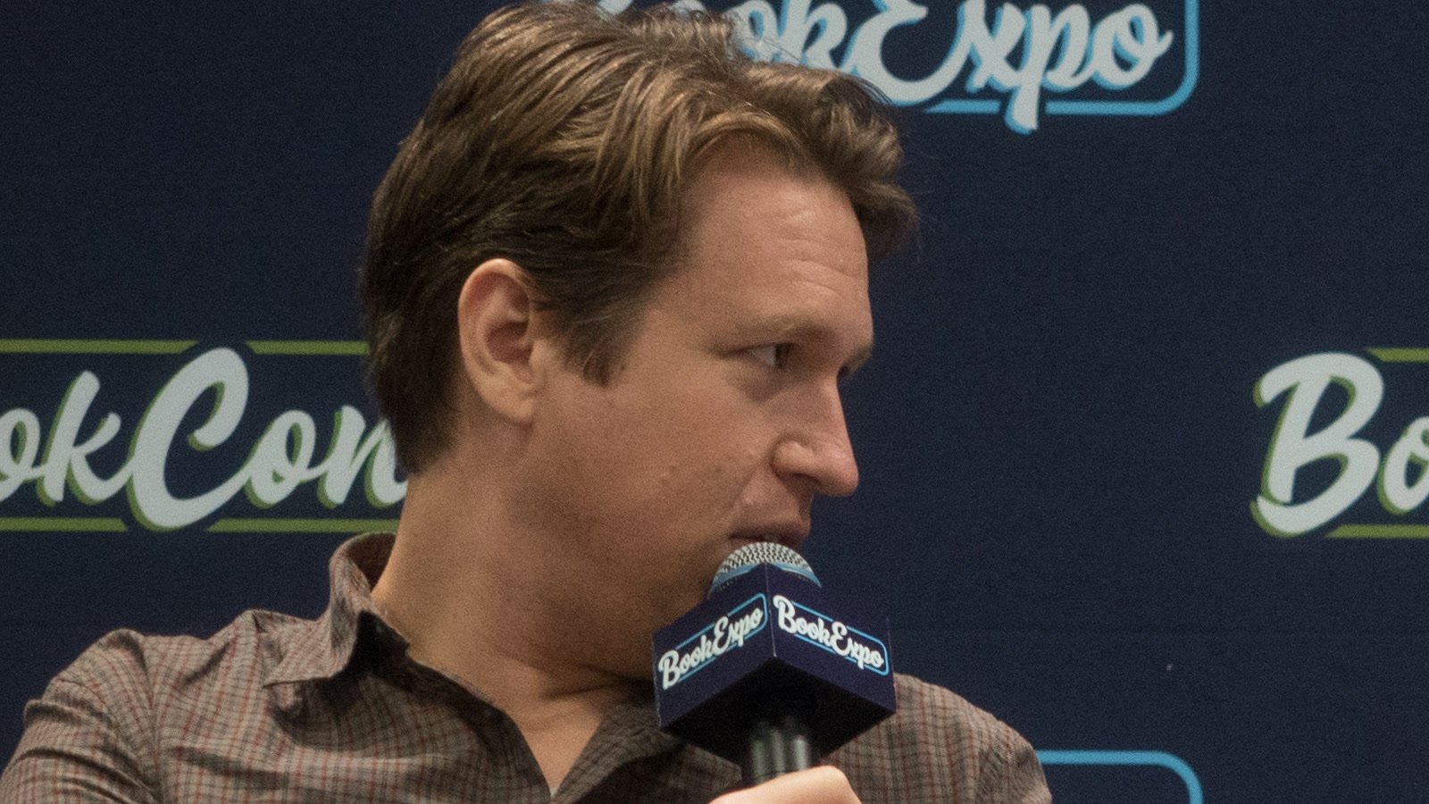 Comedian Pete Holmes speaking into a microphone at BookExpo 2019