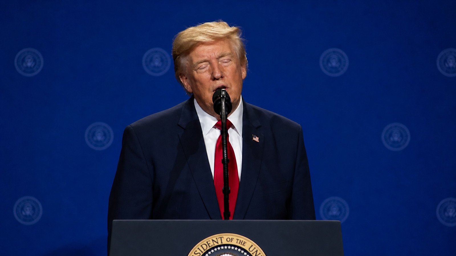 President Donald Trump speaking at a microphone
