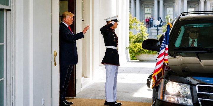 President Trump waves beside a saluting United States Marine at the White House in May 2017
