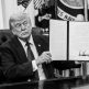 President Trump holds a signed document in the Oval Office